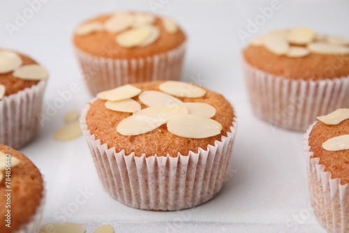 Muffins with fresh almond flakes on white tiled table, closeup