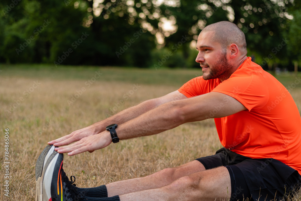A sporty man is doing stretching exercises before running or workout outdoor in the summer park active healthy lifestyle. A sporty man is doing stretching exercises before running or workout outdoor in the summer park active healthy lifestyle.