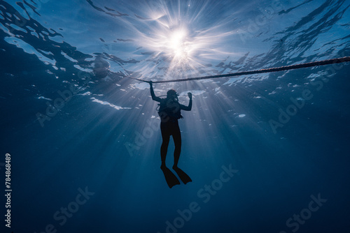 silhouette of a diver down deep with sunlight at background