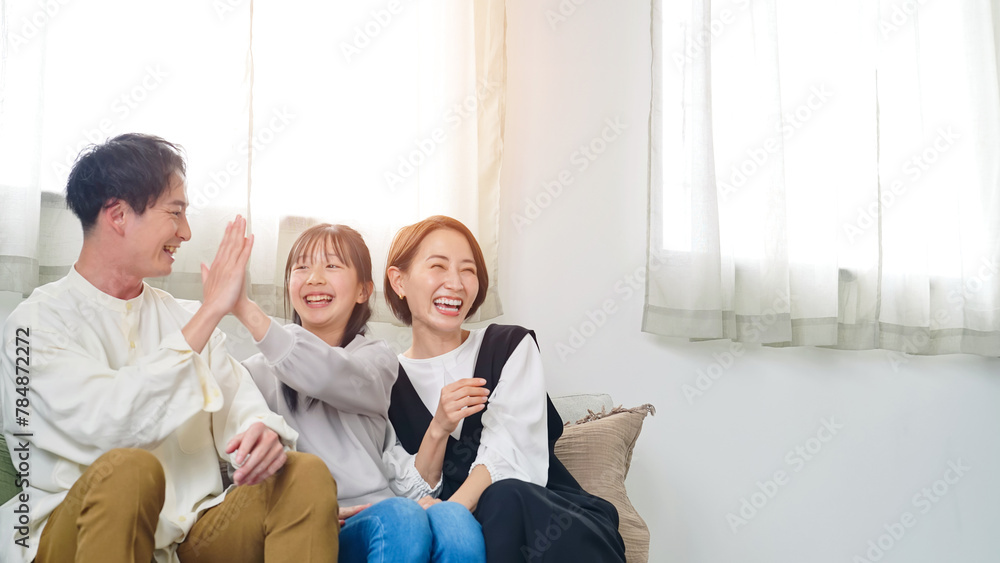 Fototapeta premium リビングルームでテレビを見ながら喜ぶ親子