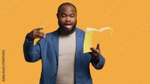 Man reading book aloud, narrating story for audience, doing monologue for theatre play. Person rehearsing using literature novel source material, reciting from pages, studio background, camera A