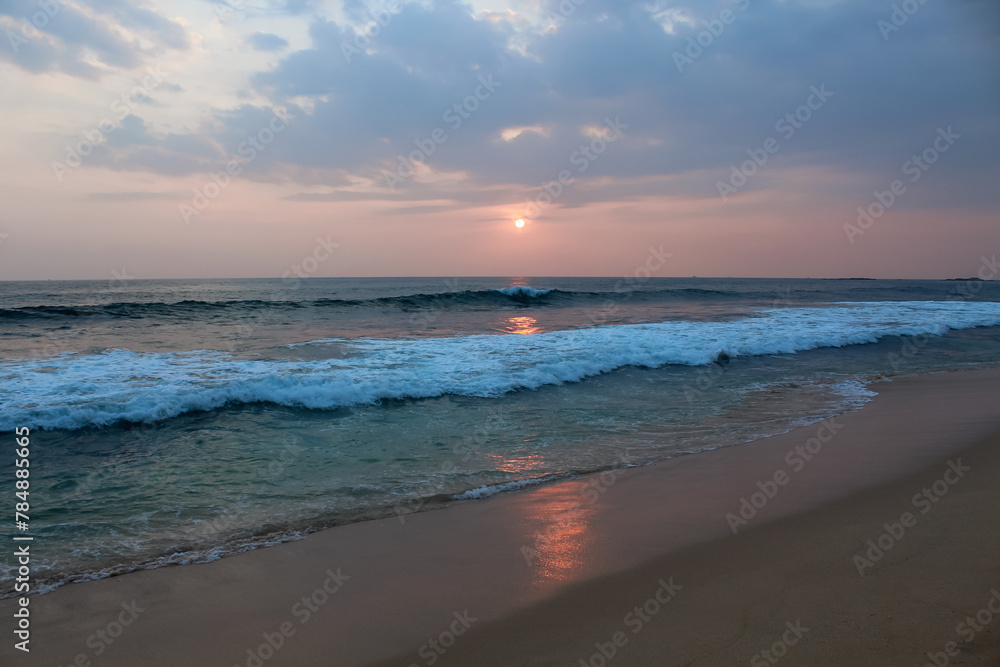 The sun setting into the sea at Delawella beach, Sri Lanka. Golden light