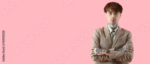 Handsome young tattooed businessman on pink background photo