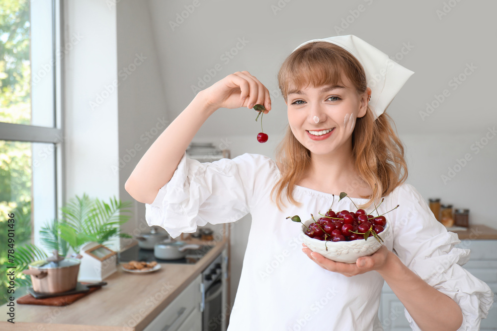 Beautiful happy young woman with bowl of cherries in kitchen Beautiful happy young woman with bowl of cherries in kitchen
