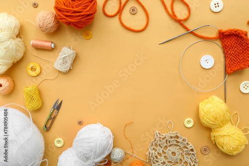 Frame made of knitting needles, yarn balls and buttons on beige background