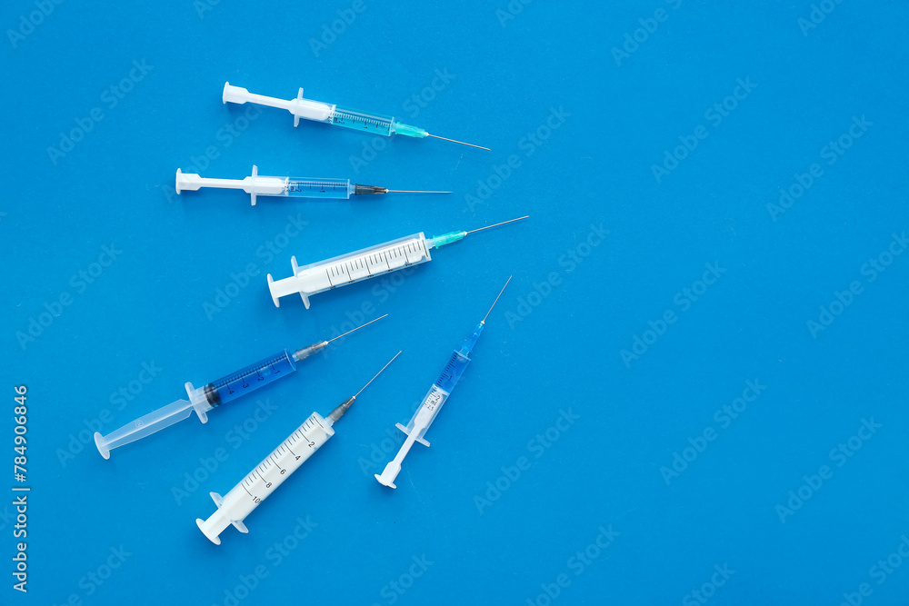 Medical syringes on blue background - obrazy, fototapety, plakaty 