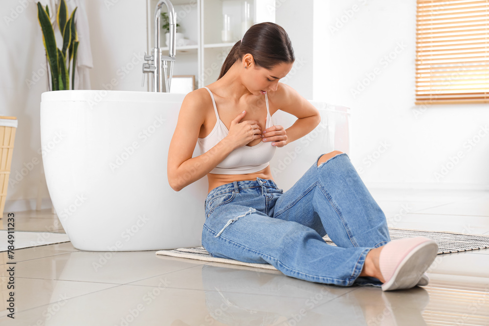 Beautiful woman checking her breast in bathroom. Cancer awareness concept Beautiful woman checking her breast in bathroom. Cancer awareness concept