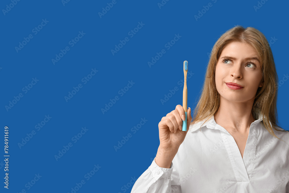 Young woman with wooden toothbrush on blue background Young woman with wooden toothbrush on blue background