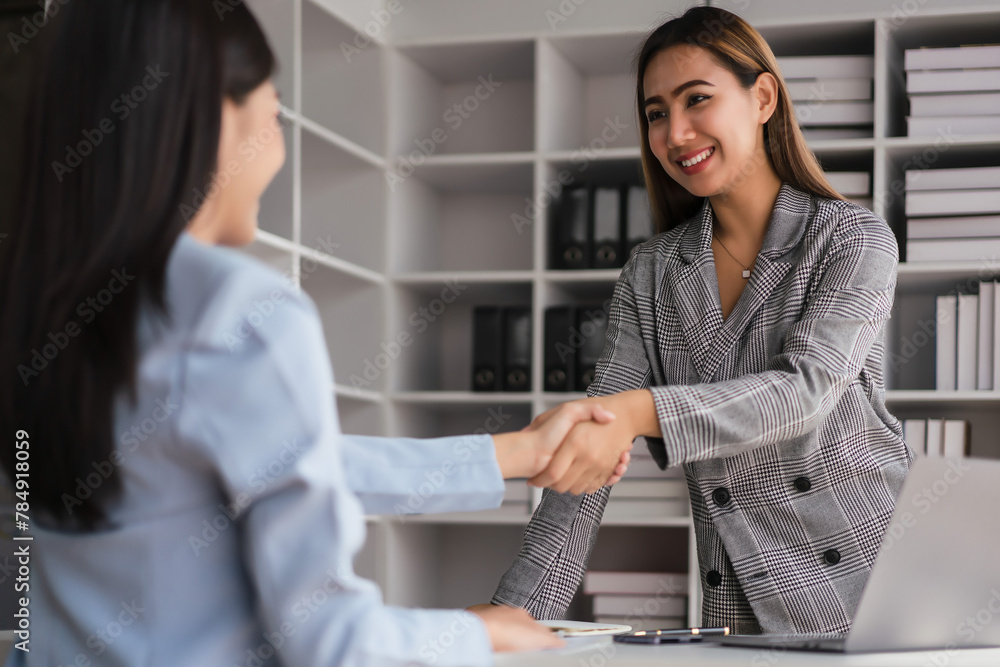 Two businesswoman shaking hands after discussion about new business project and deal together Two businesswoman shaking hands after discussion about new business project and deal together