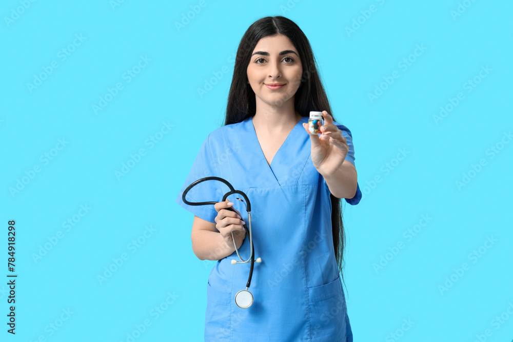 Beautiful young female doctor with stethoscope and pills on blue background Beautiful young female doctor with stethoscope and pills on blue background