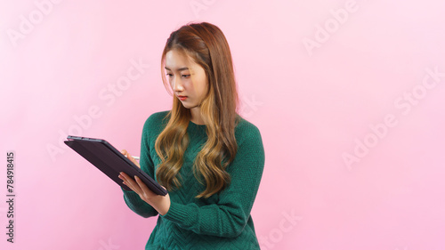 Businesswoman are working and writing business data in tablet isolated on pink background