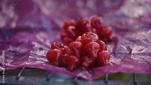 Close up of a bright red special tangy fruit called Laulau at a market stall.