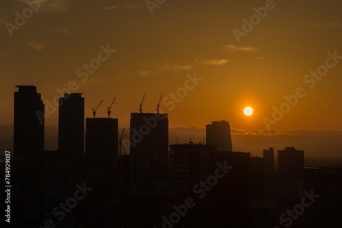 The sun is setting over a city skyline, casting a warm glow over the buildings tokyo metropolis financial