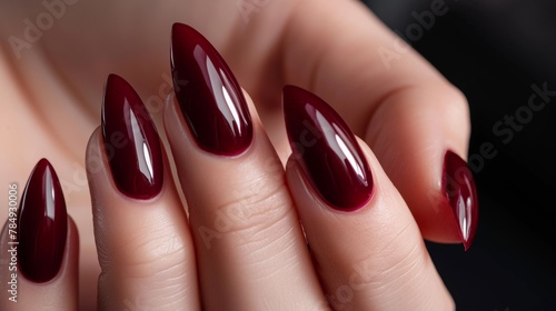 Woman hand with burgundy color nail polish on her fingernails. Burgundy nail manicure with gel polish at luxury beauty salon. Nail art and design. Female hand model. French manicure