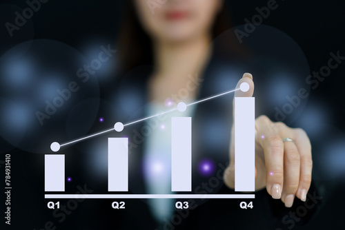 Unrecognizable good looking and smart businesswoman pointing her finger on the holographic or hologram bar chart showing a growth of business in quarter. Business concept. photo