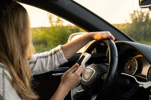 Tableau sur toile Womandriver using mobile phone paying for parking and navigating in the city while stopped on the side of the road