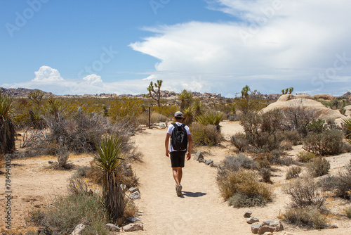 Young man hiking with backpack on Arch Rock Trail in Joshua Tree National Park, California, USA