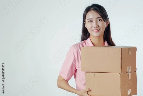 a woman asian logistic staff wearing pink shirt holding a big cardboard package, white background © cristian