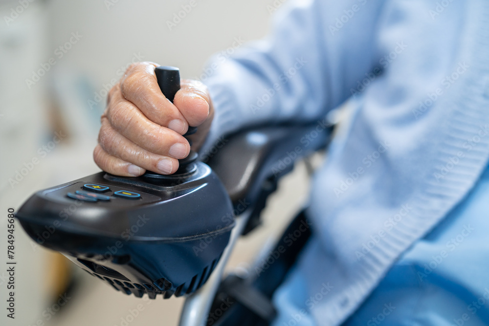 Asian senior woman patient on electric wheelchair with remote control at hospital.