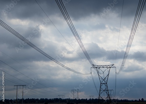 Electricity pylons and overhead cables isolated against a moody and overcast sky