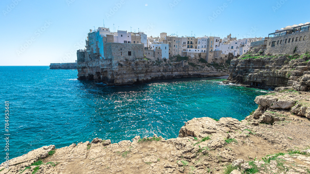 Wide panorama of Polignano a mare, a beautiful city in Puglia, italy, on a sunny day. Visible beach coming to the sea and the old town next to it. Spring or summer setting