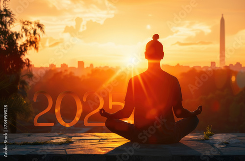 The silhouette of the number "2025" is made up by yoga postures, set against an orange sunset sky with the sun setting in front of it