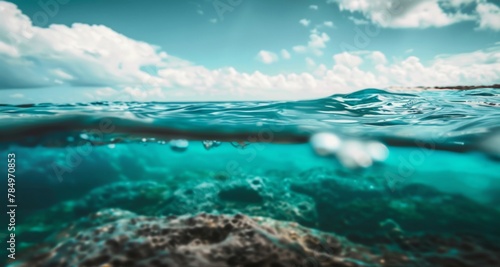 Split underwater and above-water view showing gentle waves and clear blue water bathed in sunlight.