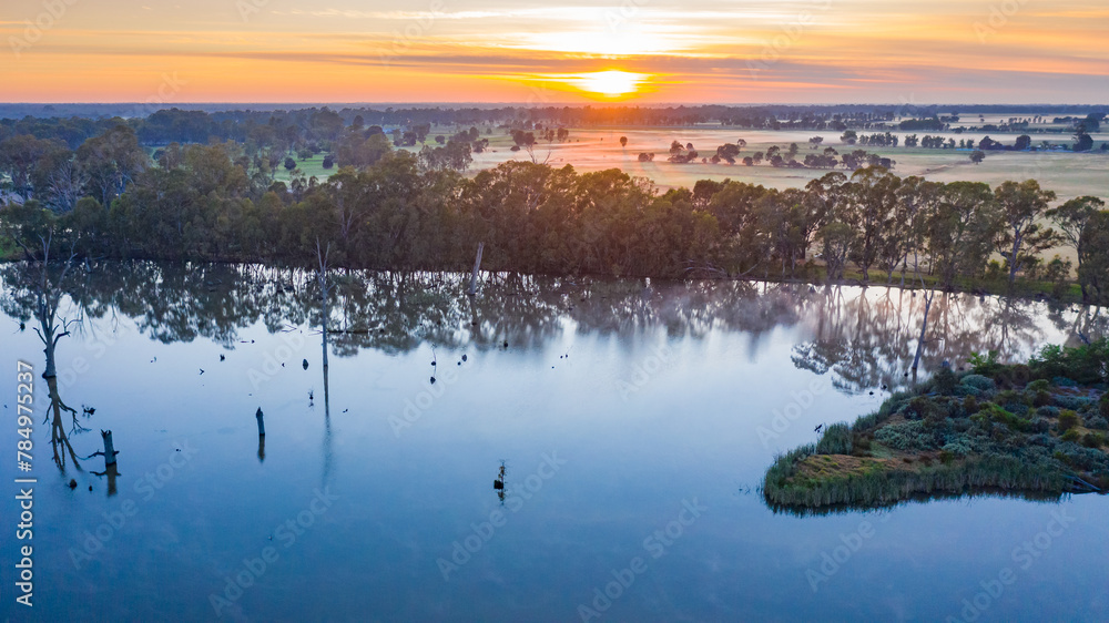 Aerial view of a cloudy sunrise over farmland alongside a still river Aerial view of a cloudy sunrise over farmland alongside a still river