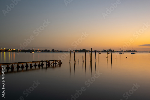 Poles of an old heritage wharf with reflections taken at blue hour / golden hour photo