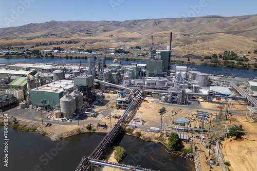 Industrial Facility with Towers and Smoke Against a Mountainous Backdrop from an Aerial Perspective