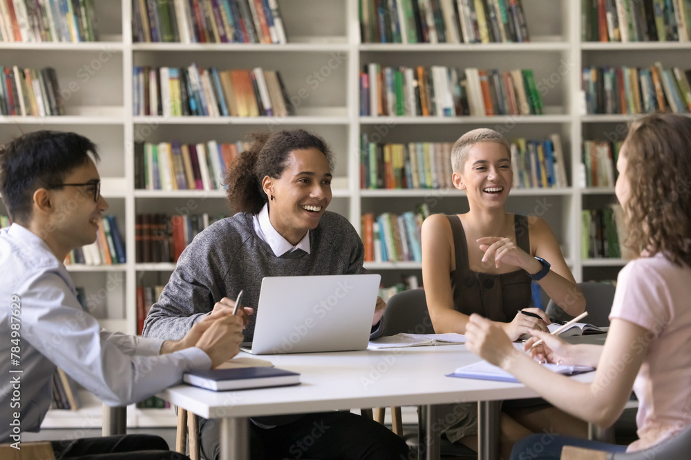 Group of happy multiracial students gathered in college library, laughing, distracted from studies, share funny stories enjoy communication, friendship and successful teamwork during class. Education Group of happy multiracial students gathered in college library, laughing, distracted from studies, share funny stories enjoy communication, friendship and successful teamwork during class. Education