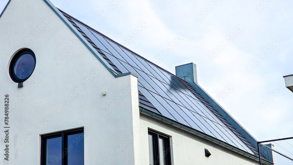 Newly built houses with black solar panels on the roof against a sunny sky Close up of new building with black solar panels. Zonnepanelen, Zonne energie, Translation: Solar panel, Sun Energy