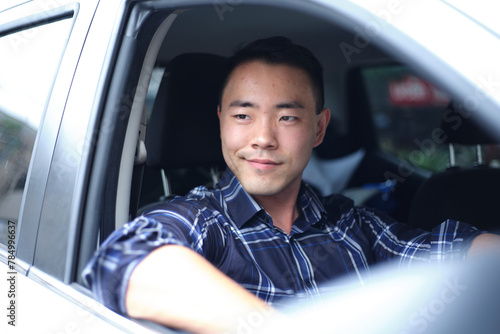 Asian man in driver's seat of car photo