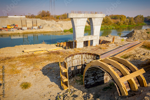 Wood arch molds at building site, huge pole in foundation with metal piles, construction of concrete-reinforced bridge pillars