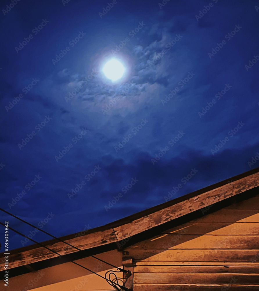 The full moon over the rooftop shines so brightly - obrazy, fototapety, plakaty 