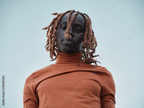 South sudanese man in orange turtleneck looking downwards