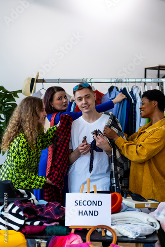 Man shopping vintage clothes in second hand store with girl friends. Used shirts, jackets, bags get second life. Swap exchange concept. Sustainable living, conscious consumption, eco friendly