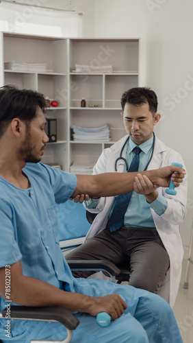 Physical therapist helping a patient while stretching his legs on a bed in a clinic or hospital. Young man attends a physiotherapy course on muscle weakness pain. and heel pain with elastic