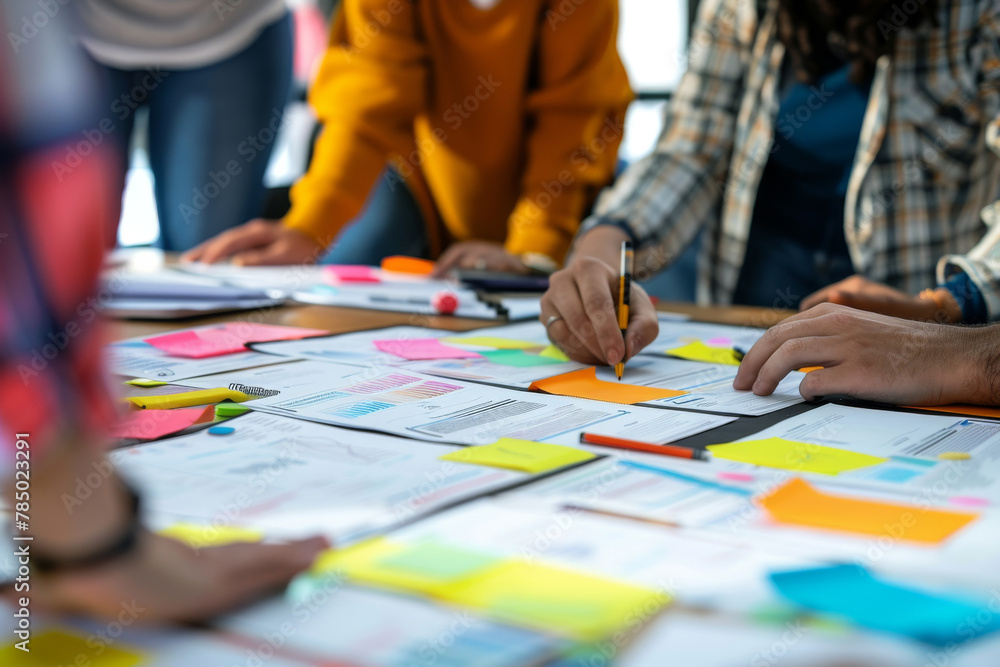 A group of people are working on a project together. They are using sticky notes to brainstorm ideas and are writing on them with pens. Scene is collaborative and creative