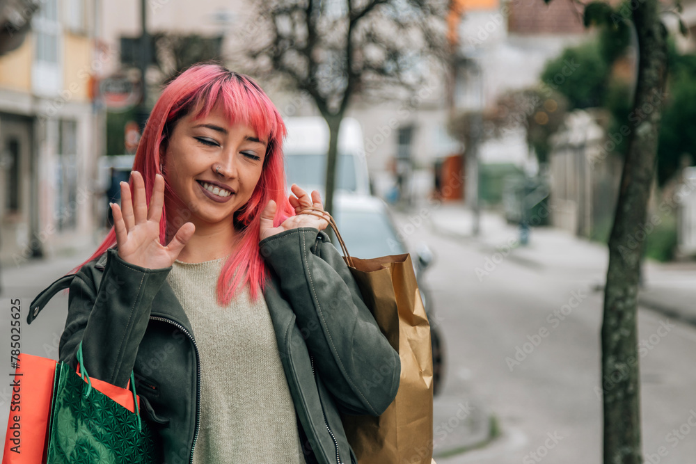 Fototapeta premium urban young woman waving with shopping bags on the street