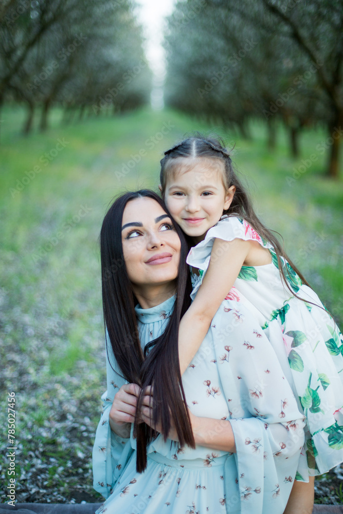A happy family. Mother and daughter rest in the park in dresses A happy family. Mother and daughter rest in the park in dresses