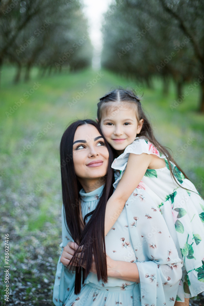 A happy family. Mother and daughter rest in the park in dresses A happy family. Mother and daughter rest in the park in dresses