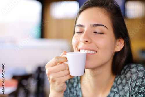 Happy woman smelling coffee in a restaurant nterior photo