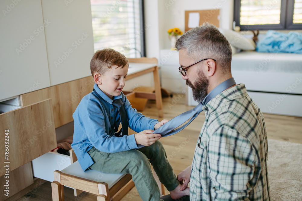 Fototapeta premium Father teaching son how to tie a tie. Memorable moment for young boy.