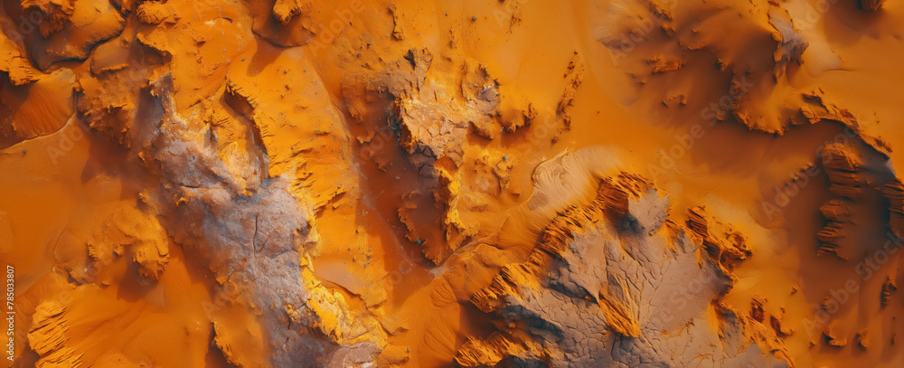 Aerial perspective captures the intricate patterns and textures of a vast, orange-colored desert landscape.