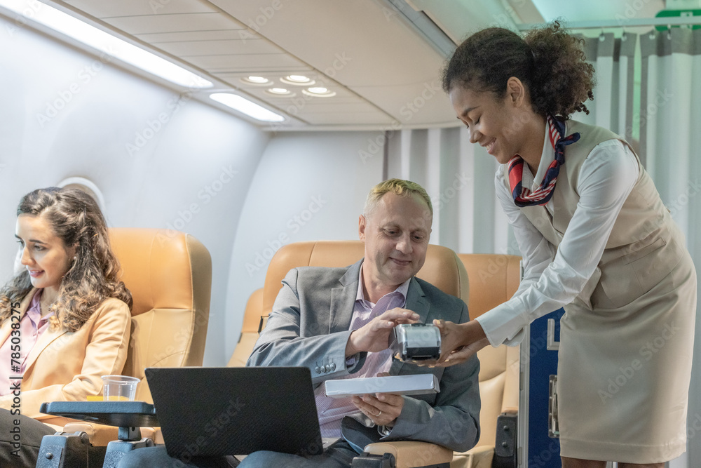 Obraz premium Business Travelers Making Purchases With a Female Flight Attendant on Board