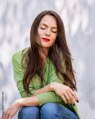Outdoor portrait of young woman with closed eyes and red lipstick