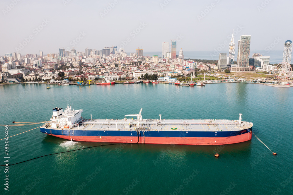 Tanker moored at oil terminal, intricate part of global petro resource trade, aerial view from drone. Key hub in industry logistics and distribution. Essential in the chain of energy supply and