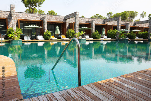 Outdoor swimming pool with wooden deck and sunbeds at resort