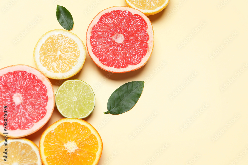 Different cut citrus fruits and leaves on beige table, flat lay. Space for text Different cut citrus fruits and leaves on beige table, flat lay. Space for text